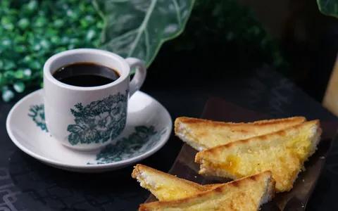 A cup of black coffee beside slices of buttered toast